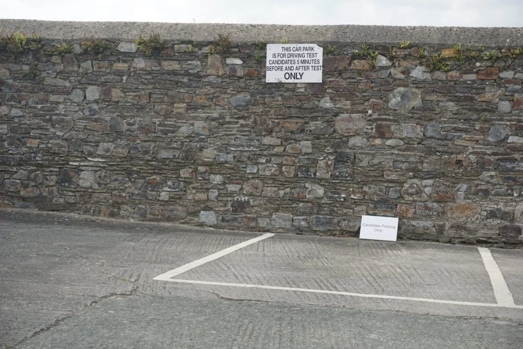 Sign on a stone wall reserving the car park for test candidates 5 minutes before and after their test