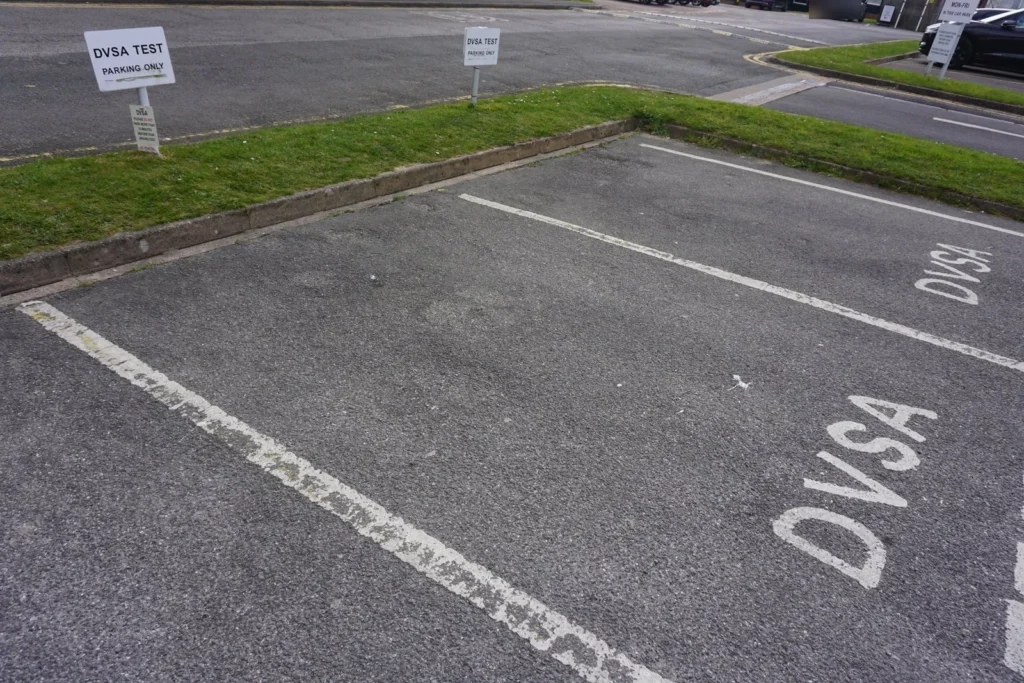 Empty parking bays each painted with DVSA, with small DVSA test parking signs on posts behind