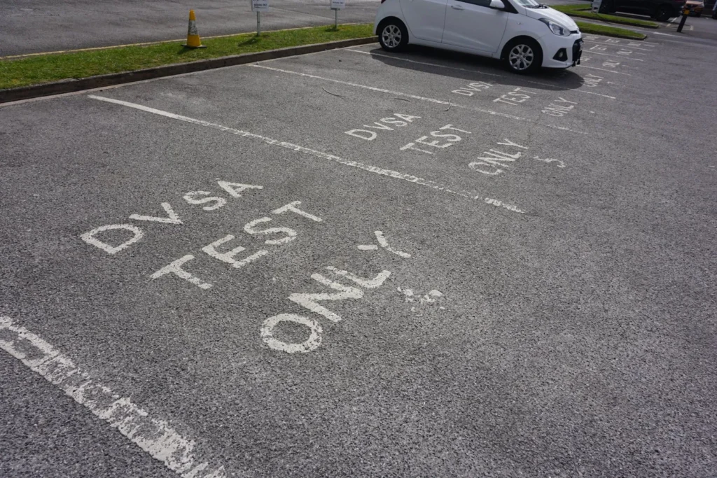 Parking bays with DVSA TEST ONLY painted in white, and a small white car parked in the next row
