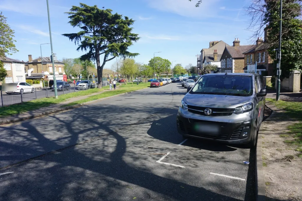 Silver van parked in a marked roadside bay, with an empty bay behind it on a sunny street