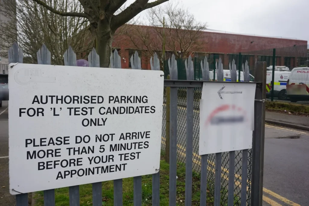 Sign on railings reserving parking for L test candidates and asking them not to arrive over 5 minutes early