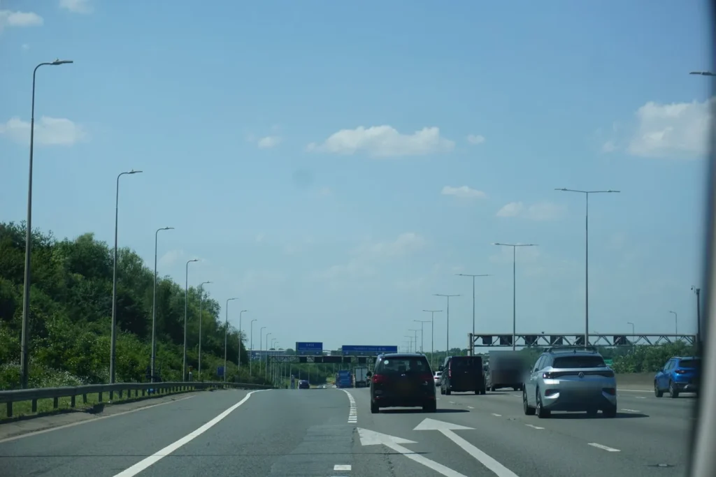Motorway lanes with painted arrows splitting at a junction, overhead gantry signs and traffic ahead